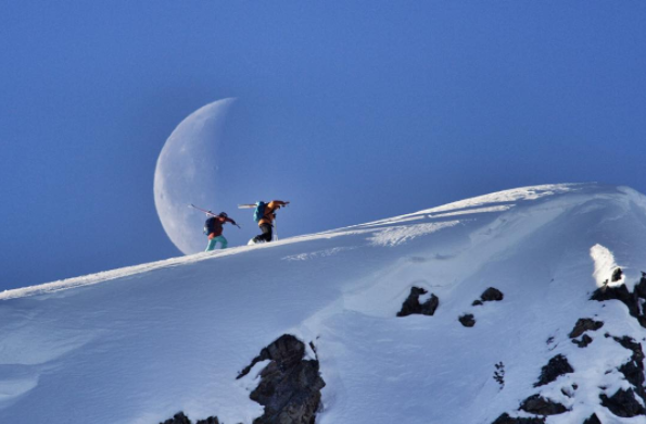 Michelle Parker and skier on the mountain in front of the moon.