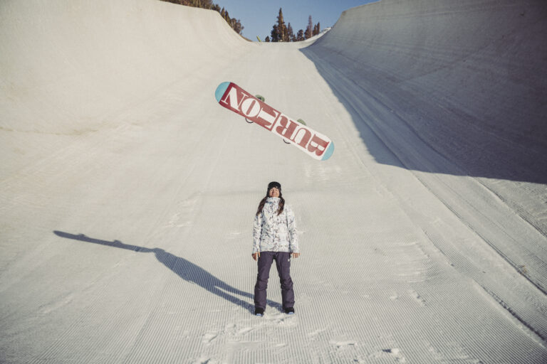 Olympic snowboarder Clark with her snowboard in the air.