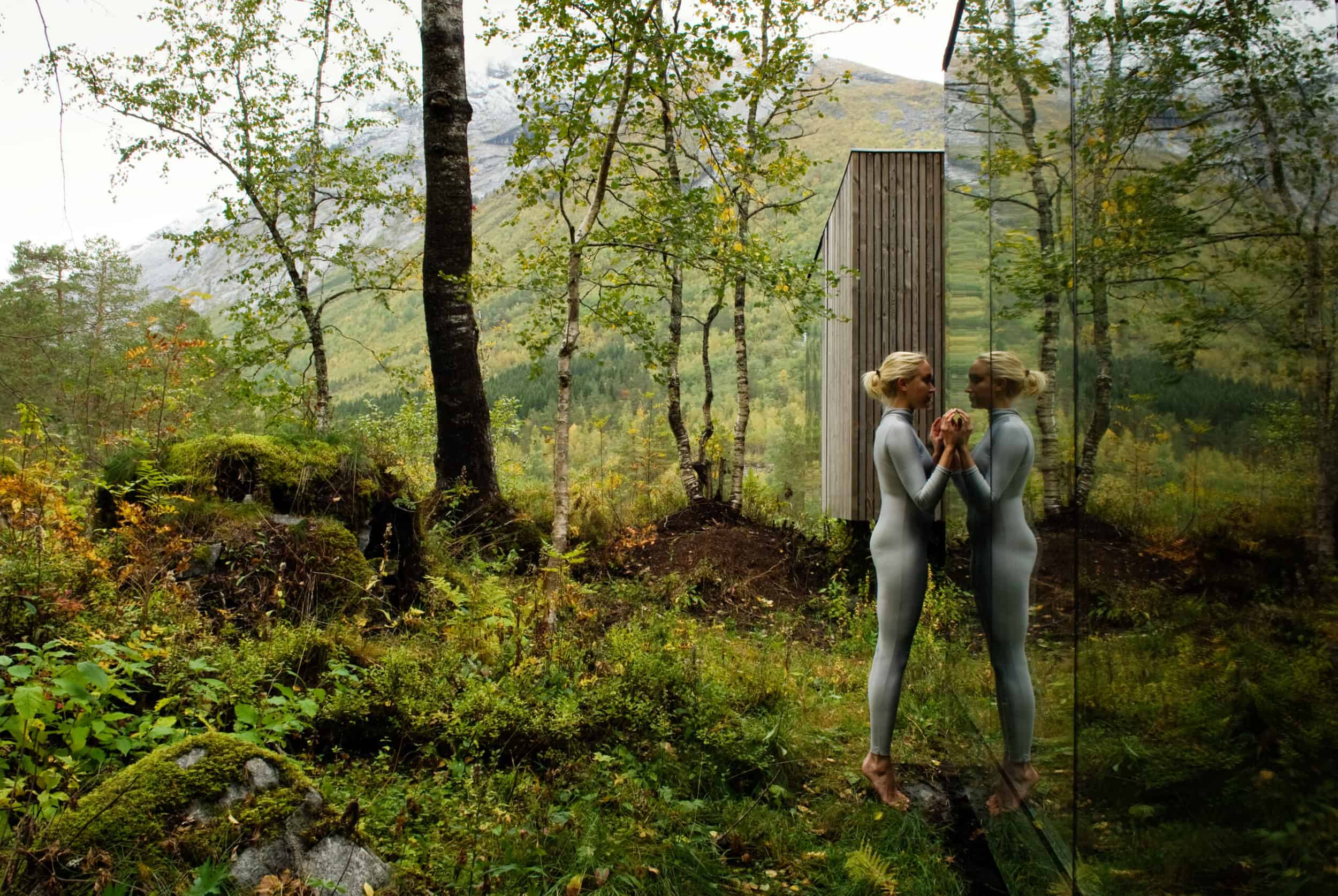 Woman looking at herself in a mirror in the woods for Juvet Landscape Hotel.