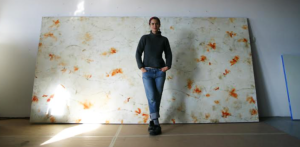 Abstract artist, Betsy Eby, standing in front of her painting.