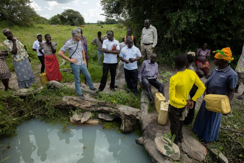 Scott Harrison with a community of people around a pool of water.